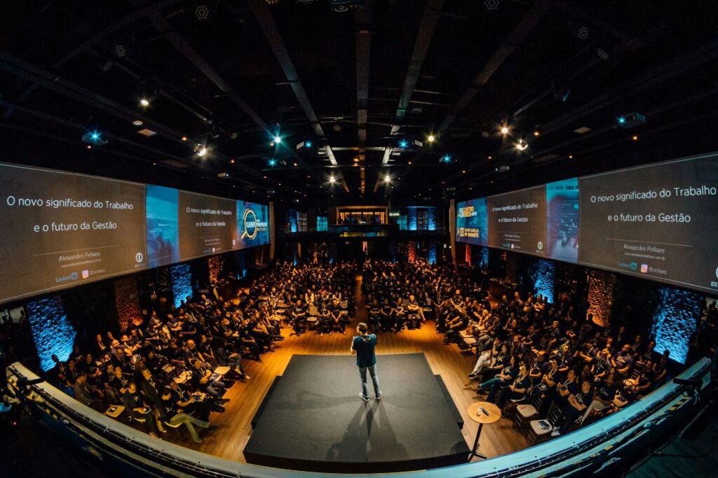 A speaker on stage addressing a large conference audience