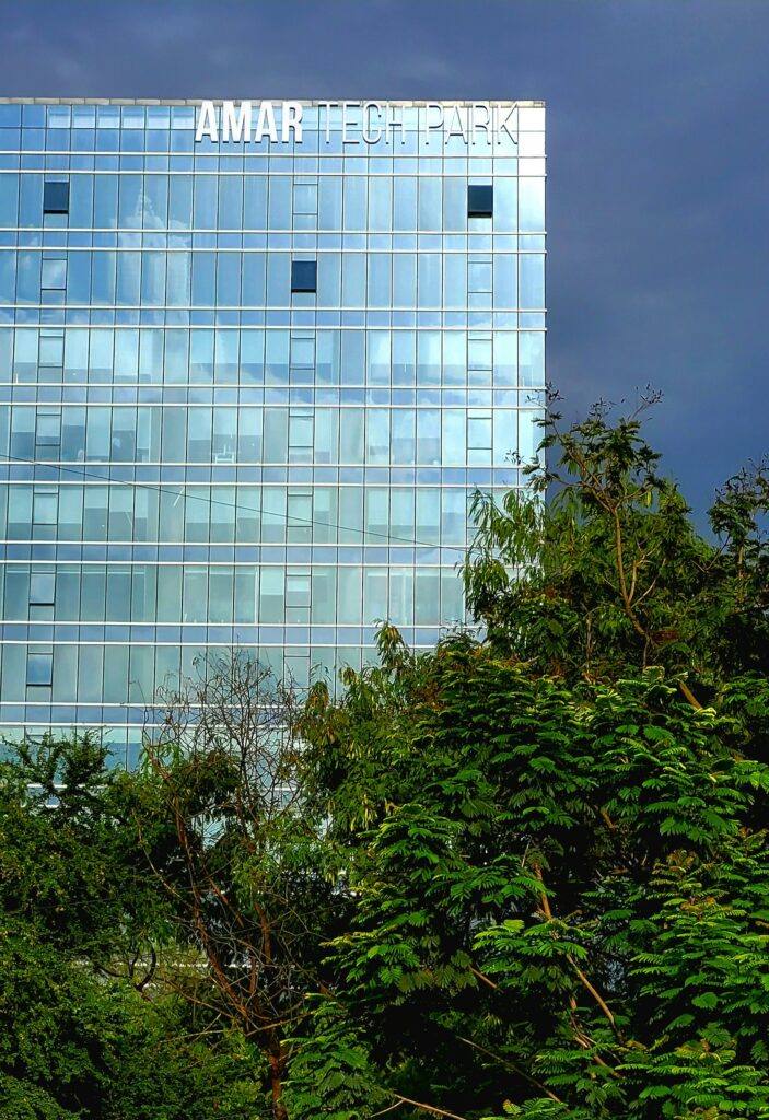 A tech park building with a glass facade above green trees in Bengaluru, India