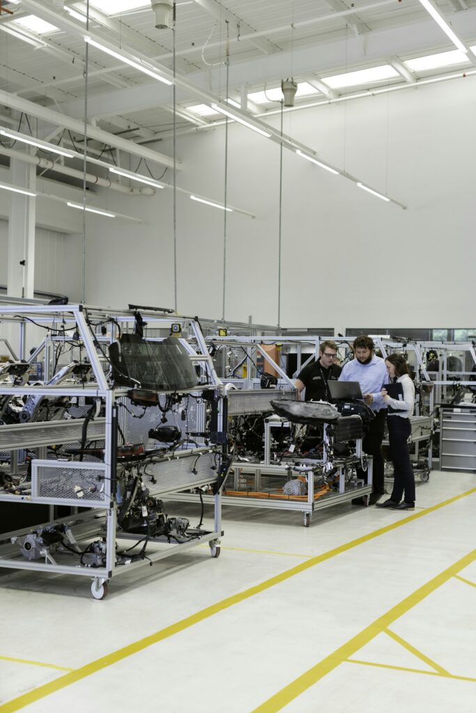Engineers working together on the floor of an automotive factory