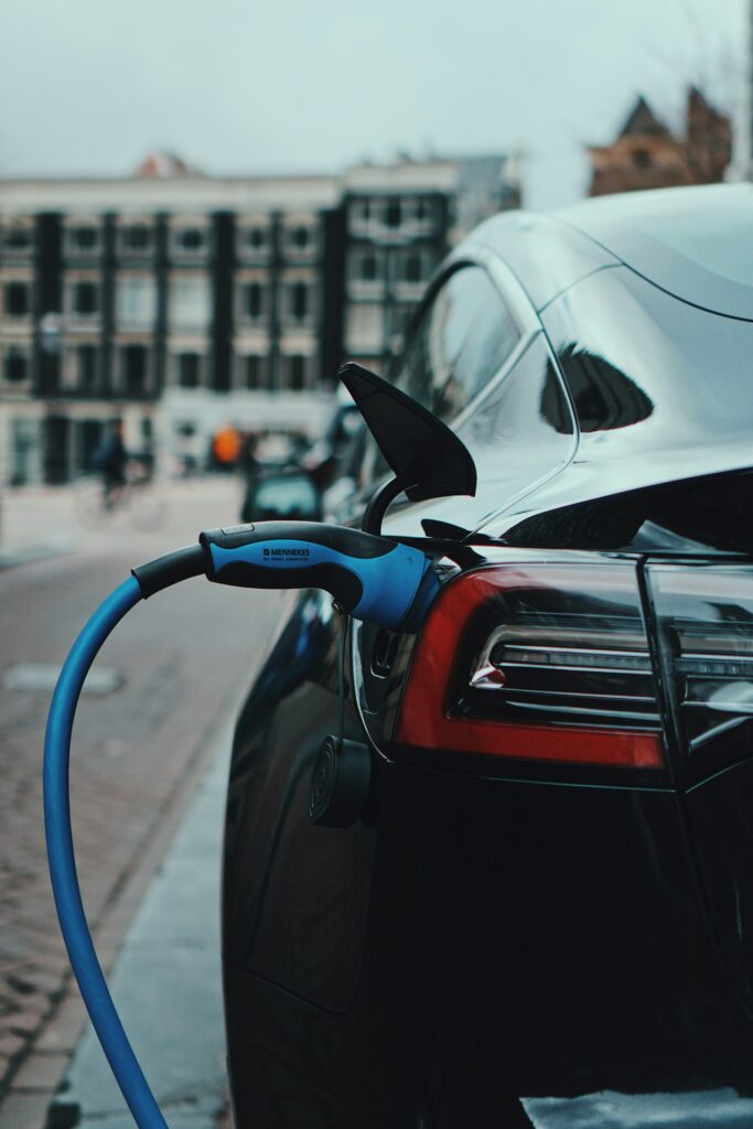 A black electric car charging on a city street
